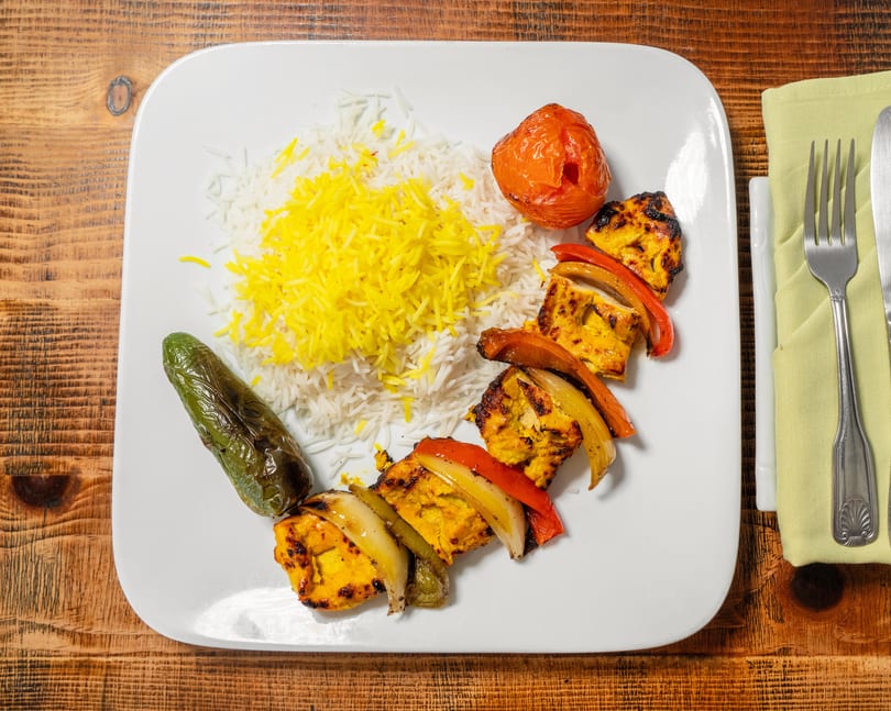 Chicken shish kebab with bell peppers and onions, rice, roasted tomato, and green pepper.