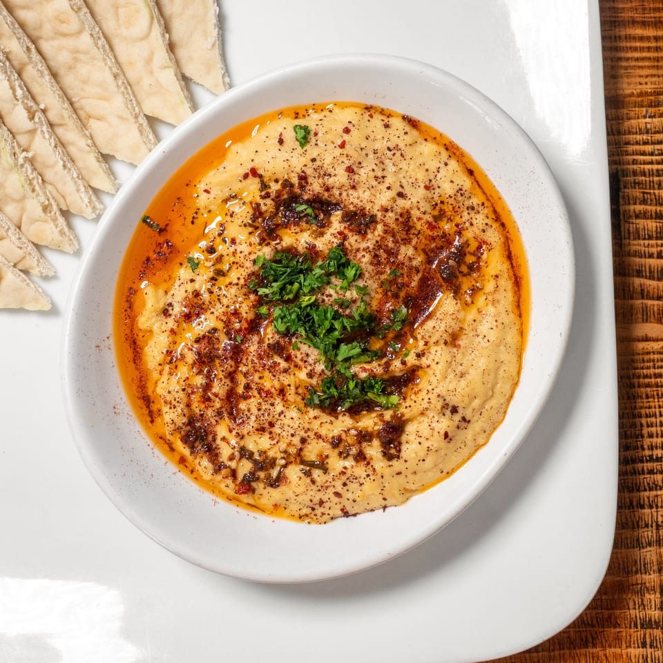 Hummus topped with paprika, olive oil, and parsley, served with pita bread.